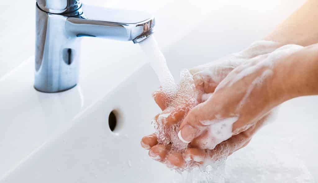 Femme se lavant les mains dans un évier avec du savon