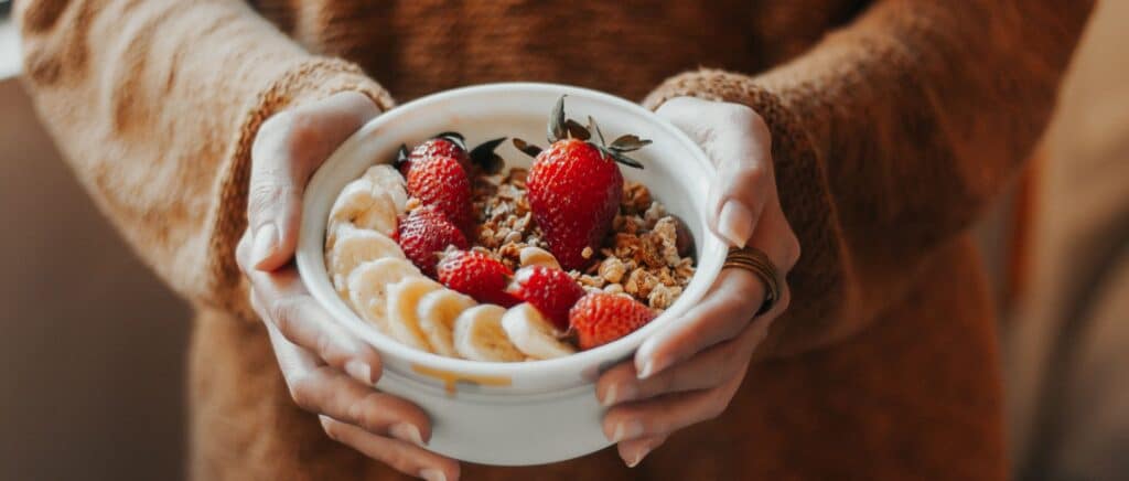woman holding Bowl of granola with fruits on top