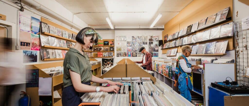 Woman standing in vinyl record shop surrounded by people
