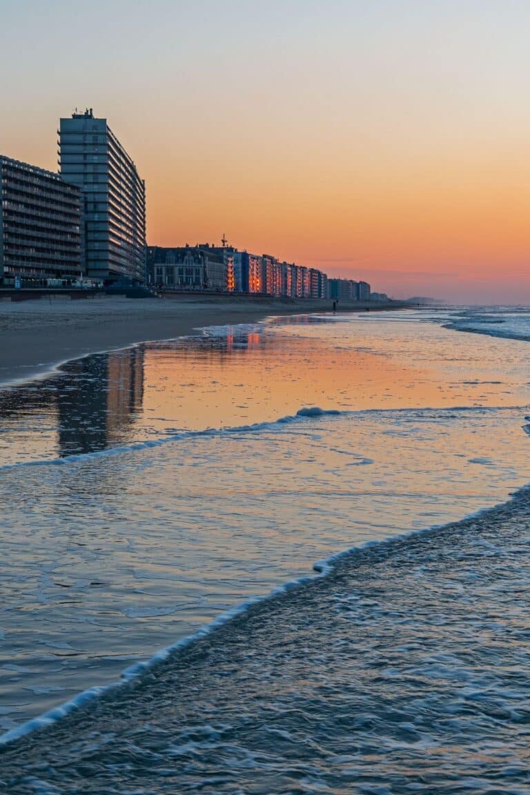Sunset view of the Ostend coastline with sandy beach and blue-orange sky.